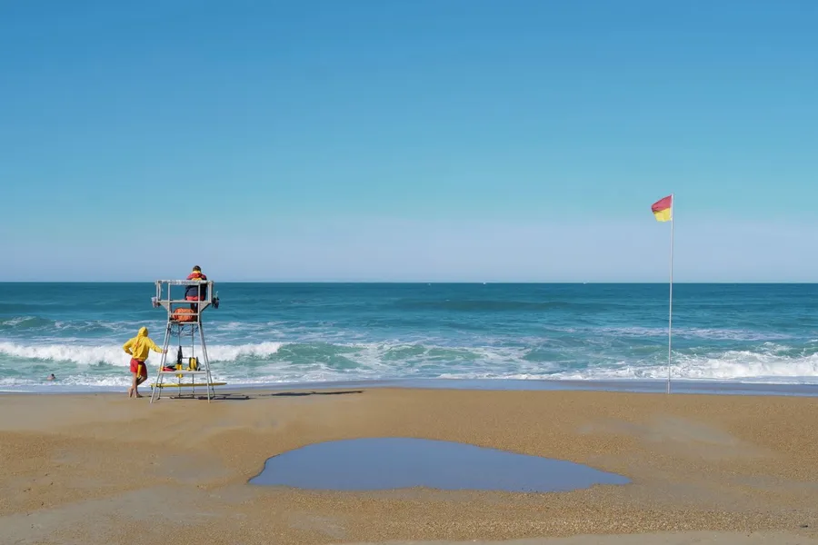Une plage avec des sauveteurs et un drapeau de sécurité